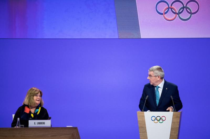 En kvinna och en man från IOK på ett podium