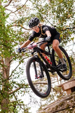 Ung kvinna kör mountainbike nerför en backe.