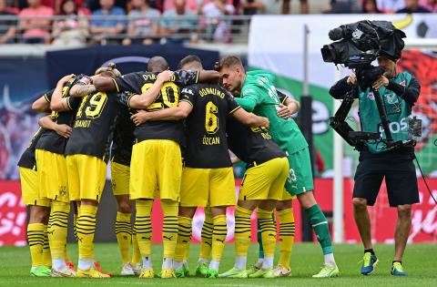 Fotbollsspelare samtalar i grupp. En kamera registrerar.