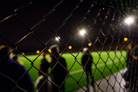 Personer vid en upplyst fotbollsplan 