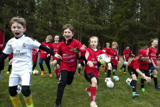 Springande barn i idrottskläder på ett grönt fält